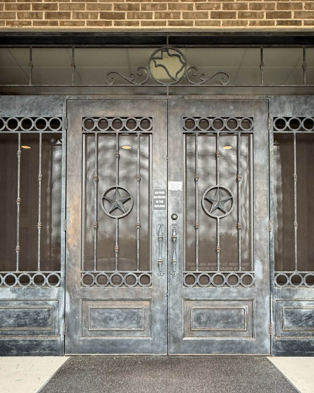 Wrought iron double doors with Texas stars before — weathered
